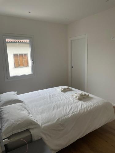 a white bedroom with a large bed with a window at G83Home-Appartamento moderno in zona Fiera in Vicenza