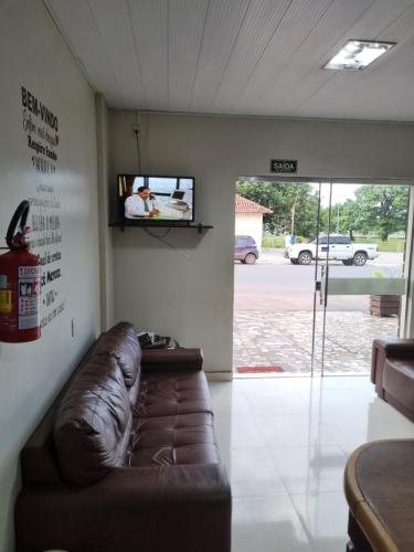 a living room with a couch and a tv on a wall at Portobello Hotel Orla in Santarém