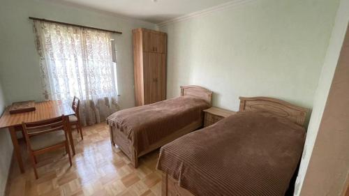 een kamer met 2 bedden, een tafel en een bureau bij Green Garden in Idzjevan