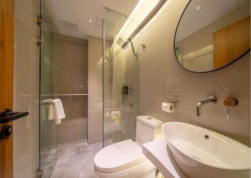a bathroom with a toilet and a sink and a mirror at MARHAUS Hotel Beijing Road Tian-Zi Pier Store in Guangzhou