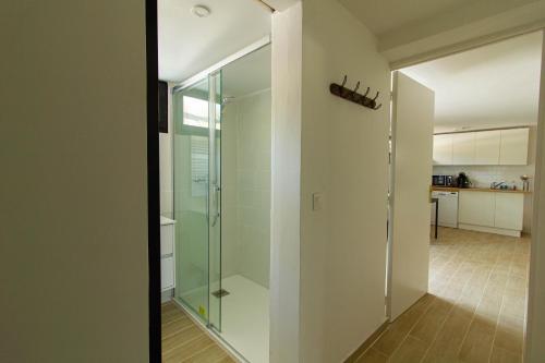 a glass shower door in a room with a kitchen at Pyla sur mer proche plages appartement avec piscine in Pyla-sur-Mer