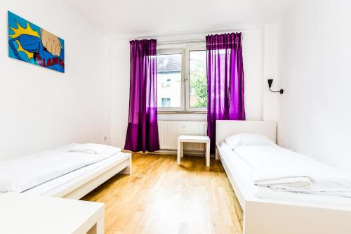 two beds in a room with purple curtains at WelcomeCologne Apartments in Cologne
