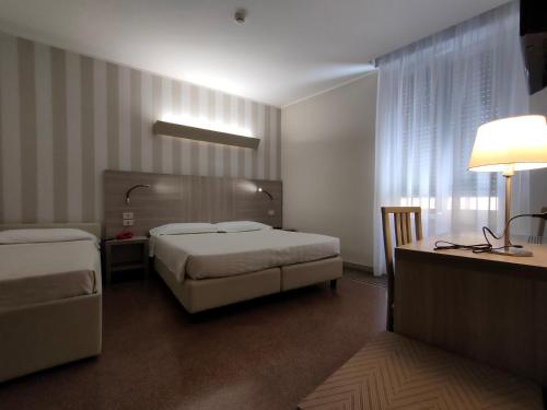 a bedroom with two beds and a desk with a lamp at Hotel Vittoria in Genova