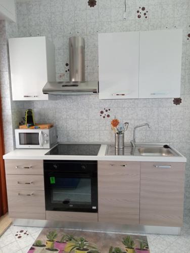 バーリにあるCasa Vacanze MaMareの白いキャビネット、シンク、電子レンジ付きのキッチンが備わります。