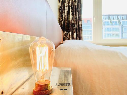 a glass lamp sitting on a table next to a bed at stunning luxury duplex downtown Knokke in Knokke-Heist