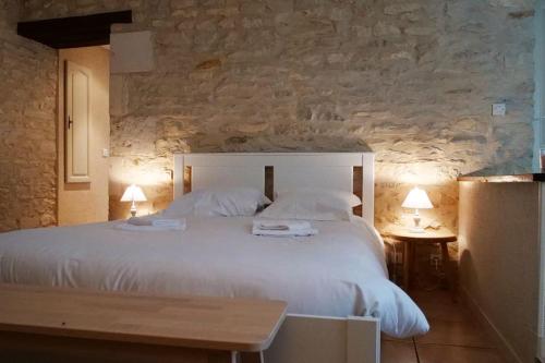 ein Schlafzimmer mit einem großen weißen Bett und einer Steinwand in der Unterkunft Le domaine de Villiers : maisons de campagne in Villiers