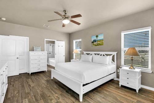 1 dormitorio con cama blanca y ventilador de techo en The Blue Pelican, en Corpus Christi