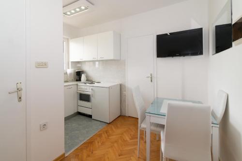 eine kleine Küche mit einem Tisch und weißen Schränken in der Unterkunft Apartments Jasna 3 in Novigrad Istria