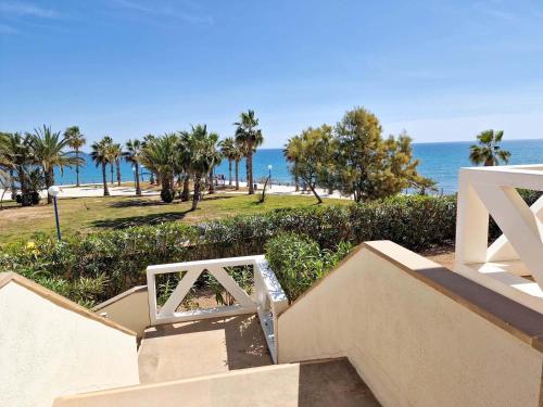 een trap naar een strand met palmbomen en de oceaan bij Frontline Beach Villa Playa Flamenca in Orihuela
