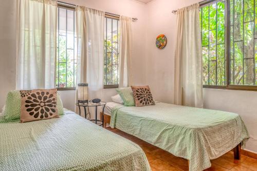 a bedroom with two beds and windows and a couch at Casa Iorio in Jacó
