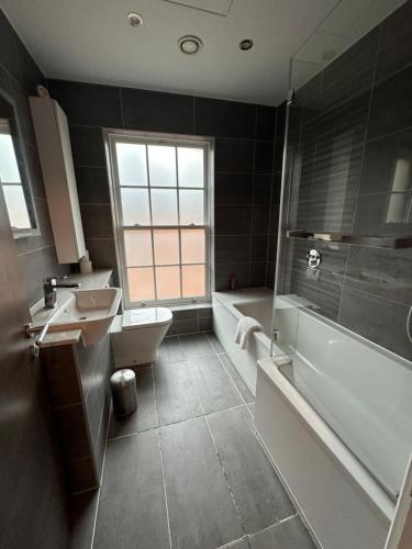 La salle de bains est pourvue d'un lavabo, d'une baignoire et de toilettes. dans l'établissement BigKings Stylish 1Bed Apartment in central Manchester, à Manchester