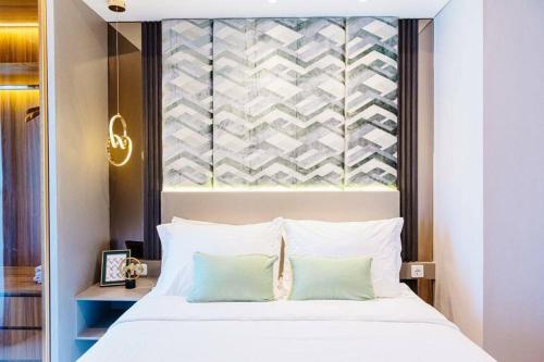 1 dormitorio con 1 cama blanca grande y 2 almohadas en kimaya at Benson Pakuwon Mall, en Surabaya