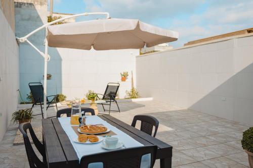 a table with food on a patio with an umbrella at Casa Alerà con idromassaggio in Lecce