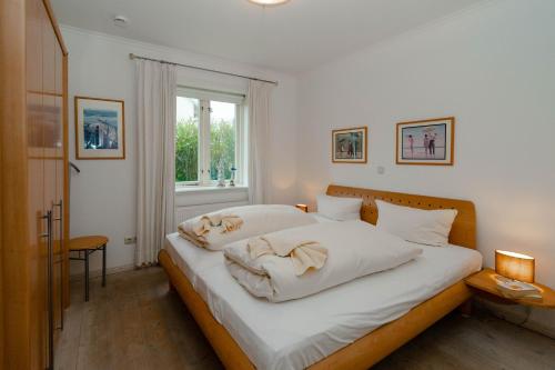 une chambre avec un lit avec des draps blancs et une fenêtre dans l'établissement Ferienwohnung Bootsmann, à Westerland
