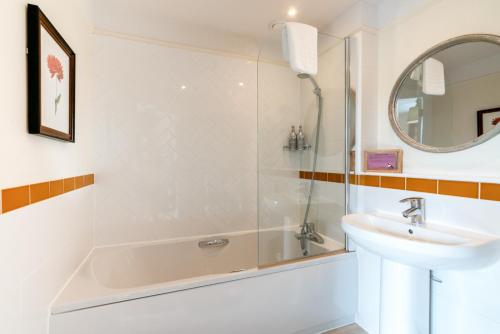 La salle de bains est pourvue d'une baignoire, d'un lavabo et d'une douche. dans l'établissement The Richard Onslow, à Cranleigh