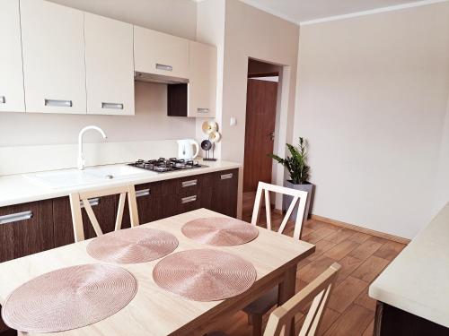 uma cozinha com uma mesa de madeira com 4 cadeiras em Apartament pod Miastem em Szamotuły