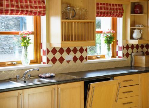 a kitchen with a sink and two windows at Dingle Courtyard Holiday Homes 3 Bed in Dingle