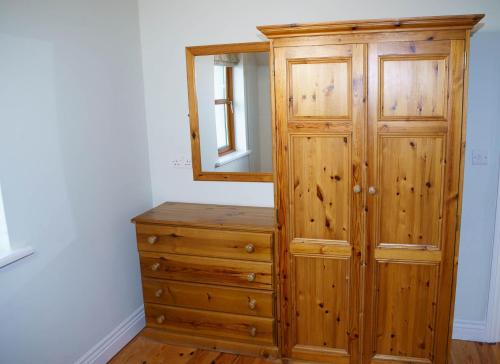 a wooden cabinet with a mirror and a dresser at Dingle Courtyard Holiday Homes 3 Bed Sleeps 6 in Dingle