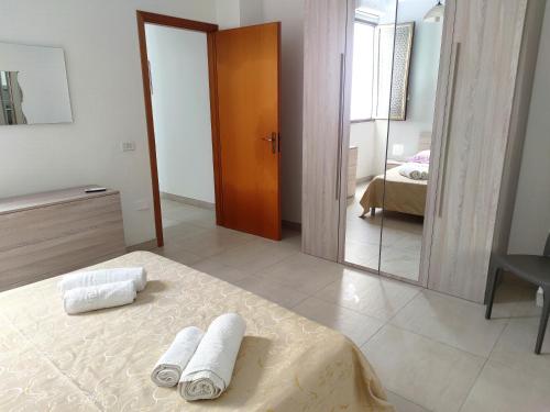 a bedroom with two towels on a bed and a mirror at My Home Lampedusa in Lampedusa