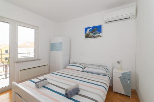 ein weißes Schlafzimmer mit einem Bett und einem Fenster in der Unterkunft Apartments Jasna 4 in Novigrad Istria