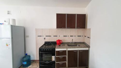 a kitchen with a stove and a sink and a refrigerator at Acacias in Mar de Ajó