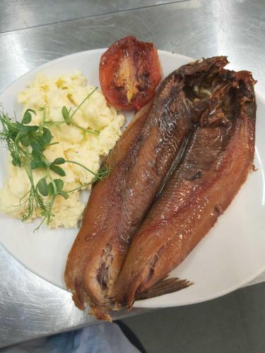 Un plato de comida con salchicha y patatas y un tomate. en The Waterford Arms, en Hartley