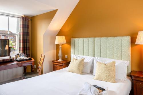 a bedroom with a bed and a desk and a window at The Richard Onslow in Cranleigh