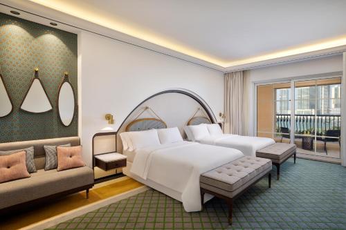 The Westin Dubai Mina Seyahi Beach Resort and Waterpark في دبي: غرفة نوم بسرير كبير وأريكة