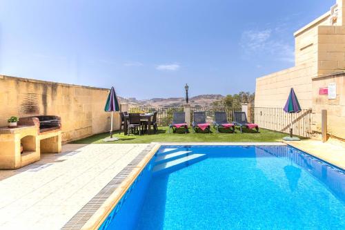 a swimming pool in a yard with a table and chairs at Ta Lucija Sleeps 4 with Private Pool in Marsalforn