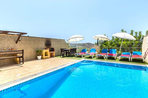 a swimming pool with chairs and a table and umbrella at Ta Guljetta 4 bedroom Villa with private pool in Marsalforn