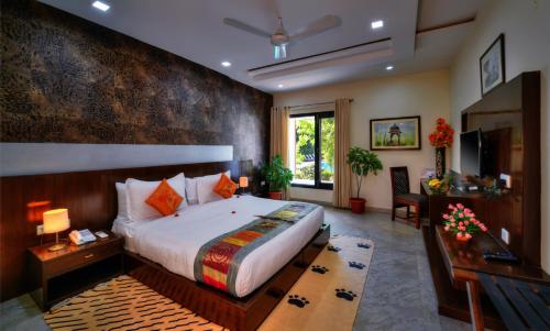 a bedroom with a king sized bed and a desk at Jungle Vilas in Sawāi Mādhopur