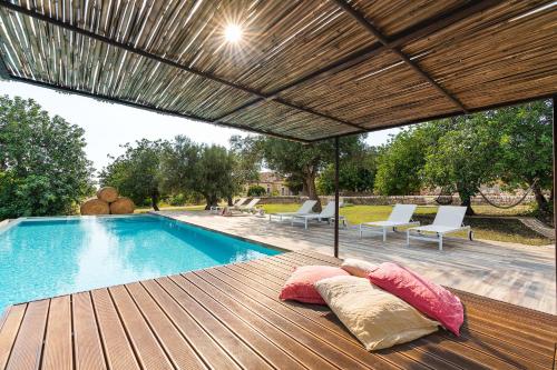 una piscina con cuscini su una terrazza in legno accanto alla piscina di Dimora Pura a Scicli