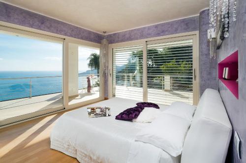 a bedroom with a white bed and a large window at Villa Luce in Letojanni