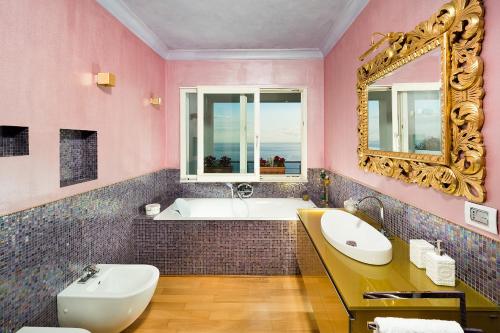 a pink bathroom with a tub and a sink and a mirror at Villa Luce in Letojanni