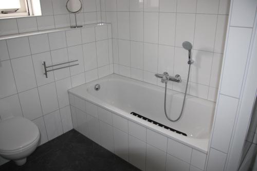 a white bathroom with a tub and a toilet at Sint-Anthonijshoek in Koudekerke