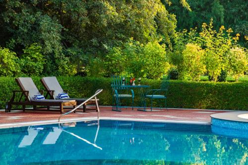 a pool with two chairs and a table next to it at Jungle Vilas in Sawāi Mādhopur