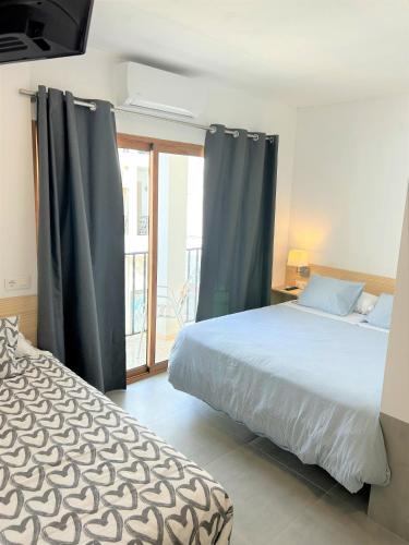 a bedroom with a bed and a large window at Hostal Fornet Altea in Altea