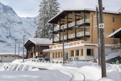 a building in the snow with a mountain at Hotel Alpenblick Mürren in Mürren