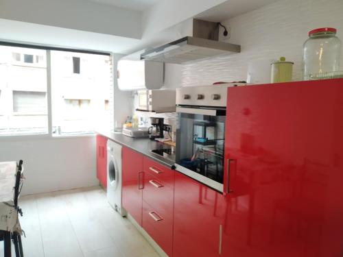 uma cozinha com armários vermelhos e uma grande janela em Apartamento GIJON LOS CAMPOS em Gijón