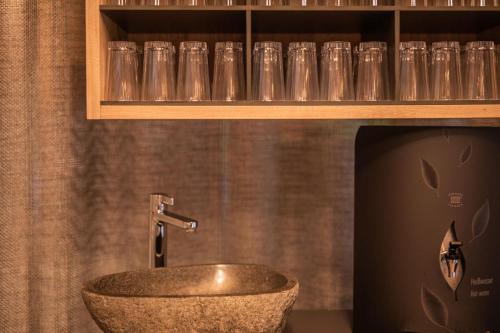 a bathroom with a sink and glasses on a shelf at Hotel Arlmont 4 Stern Superior in Sankt Anton am Arlberg
