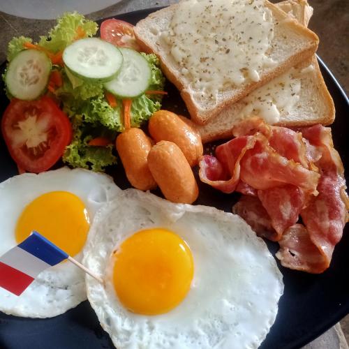 a plate of breakfast food with eggs bacon and toast at Mateoasis in Ko Kood