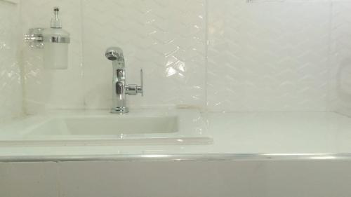 un lavabo blanco en un baño de azulejos blancos en Cabaña Recinto del Pensar, en Santa Marta