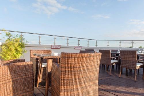 a patio with wicker chairs and tables on a deck at Ramada by Wyndham Princess Paramaribo in Paramaribo