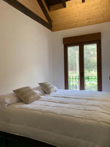 a large white bed in a room with a window at Casa Rural en Santa Cruz-Mieres in Bustiello