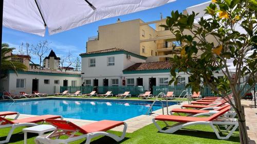 einen Pool mit Liegestühlen und ein Gebäude in der Unterkunft Moon Dreams Fuengirola in Fuengirola