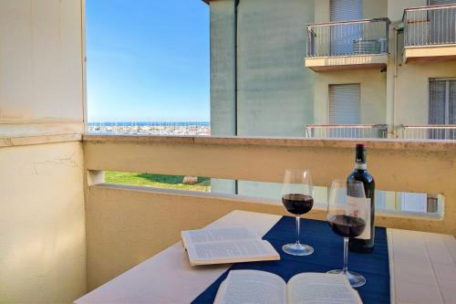 einen Tisch mit zwei Gläsern Wein und ein Buch in der Unterkunft Panorama sul mare by WeHostYou Wifi Clima Parcheggio in Porto San Giorgio