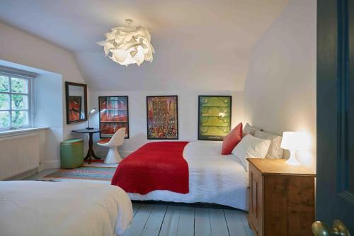 1 dormitorio con 2 camas y lámpara de araña en Sleeps 10. The Old pink library by loch and river en Lochearnhead