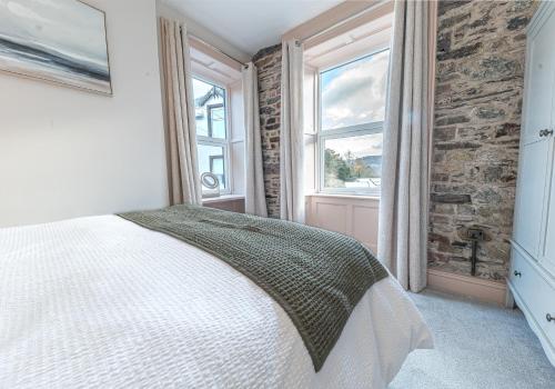 1 dormitorio con cama blanca y pared de ladrillo en Withesike, Derwent House, en Keswick