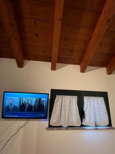 a flat screen tv on a wall with two curtains at Affittacamere Karma Rho-Fiera in Rho