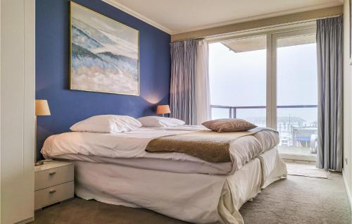 1 dormitorio con 1 cama grande y pared azul en Amazing Apartment In Cadzand-bad With Kitchen en Cadzand-Bad